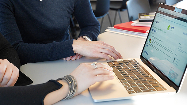 Zwei Personen arbeiten an einem Laptop.