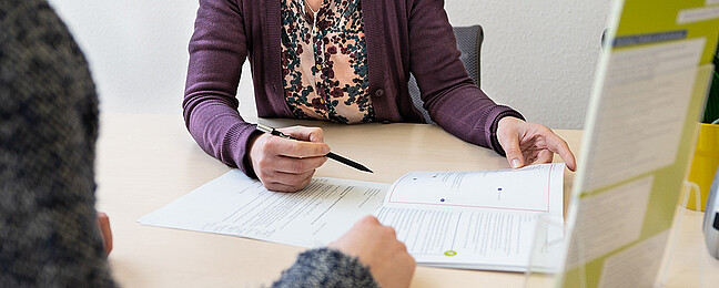 Zwei Personen im Gespräch zu Bewerbungsunterlagen während einer individuellen Beratung.